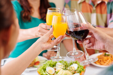 Close-up image of friends clinking glasses over dinner table at party