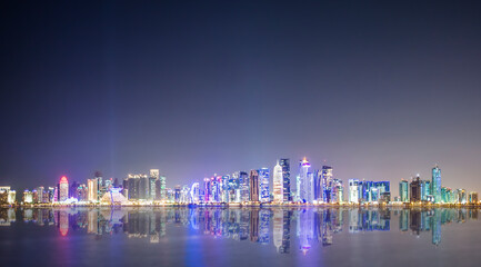 (Selective focus) Stunning panoramic view of the Doha Skyline illuminated at dusk during the Covid-19 pandemic. Doha is the capital and most populous city of the State of Qatar.