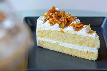 Closeup of almond cake on a black plate with natural light background.