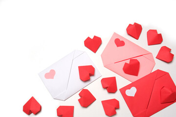 Red, pink, white paper envelopes with colored hearts, surrounded by several handmade red 3D paper hearts on white background isolated copy space. Love, Valentine's, mother's, women's day concept