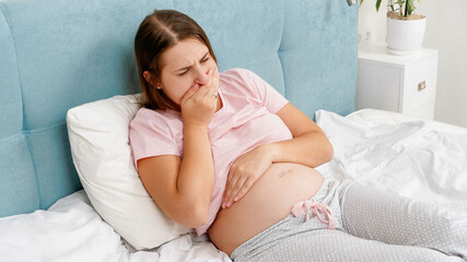 Yougn pregnant woman awake in the morning feeling unwell suffering from nausea. Intoxication during pregnancy