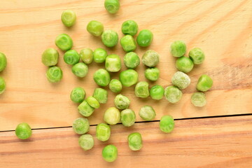 Ripe frozen green peas on a wooden table, close-up.