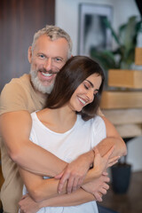 Bearded man and young woman hugging and looking happy