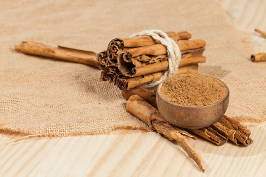 Cinnamon powder and cinnamon stick; photo on wooden background.