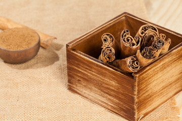 Cinnamon powder and cinnamon stick; photo on wooden background.