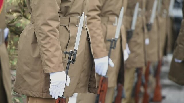 Military guard of honor holding rifles in rest position participate at a funeral in winter time