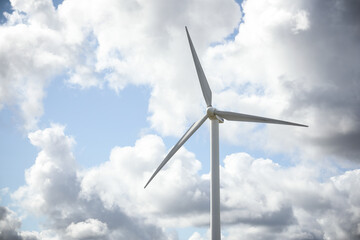 Wind turbine in a sunny day with blue sky and clouds. Wind farm eco field. Green ecological power energy generation.	