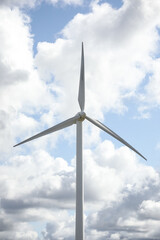 Wind turbine in a sunny day with blue sky and clouds. Wind farm eco field. Green ecological power energy generation.	