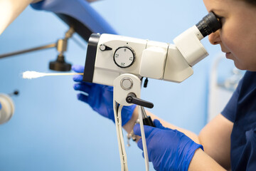 Woman ginecologist is examining patient on ginecologist seat with microscope and swab to analyse.