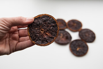 Failure at drying orange slices in oven. Person hand holding a dry and over burnt charred fruit.