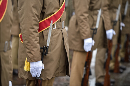 Military guard of honor holding rifles in rest position participate at a funeral in winter time