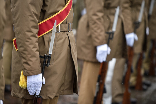 Military guard of honor holding rifles in rest position participate at a funeral in winter time
