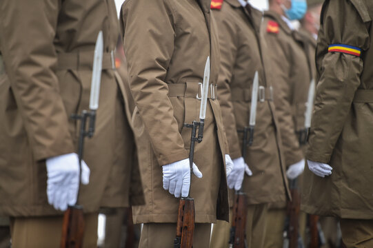 Military guard of honor holding rifles in rest position participate at a funeral in winter time