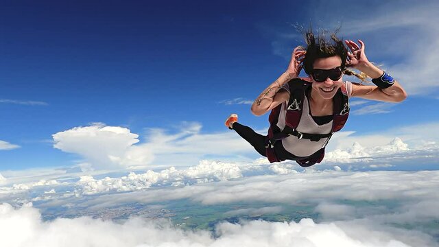 Image of a woman parachutist in casual clothing smiling and having fun in free fall. Recorded in slow motion in 4K definition.