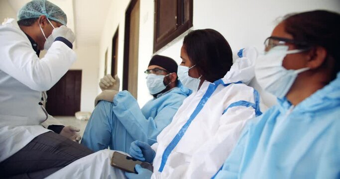 Slow-motion of doctor with lab coat with his colleagues take a break at teamwork as they bump their hands fist and high five after hours of selfless working at the frontline of the global pandemic 