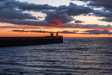 Obraz premium The North Pier Lighthouse with some dark clouds after sunset in Whitehaven, Cumbria, England, UK