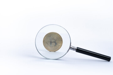 Bitcoin cryptocurrency with magnifying glass isolated on white background, selected focus. 