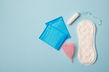 menstruation products, intimate hygiene, women gynecological health, sanitary pads, tampon and menstruation cup on blue background - obrazy, fototapety, plakaty