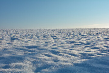 Fototapeta na wymiar Snow field with blue sky on the horizon