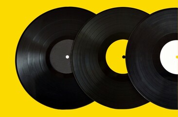 Old black vinyl records on bright yellow background close up.