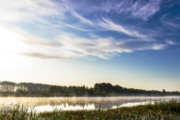Obraz na płótnie Canvas Sunrise over a swamp with fog and reeds. Sunny summer morning.