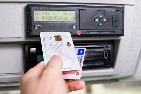 Hand Holding A Driver Digital Card And Europian Driving Licence Infront Of A Digital Tachograph. No Personal Data