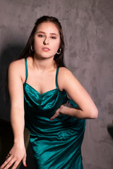 sexy attractive brunette woman in elegant green aquamarine dress in a loft cafe. beautiful sensual girl