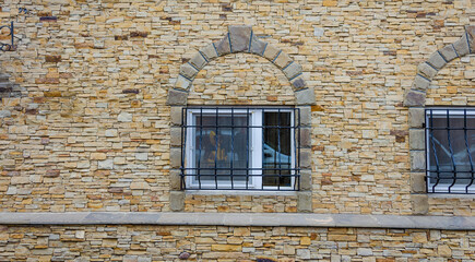 Fototapeta na wymiar A window with an iron grating in the stone wall.