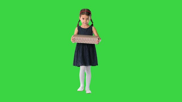 Little girl in black dress walking with a gift box in her hands on a Green Screen, Chroma Key.