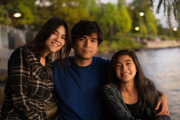 Young biracial Asian Caucasian young people by lake at sunset