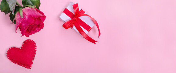 Valentines Day banner background. Red rose with red heart and a gift on a pink background with copy space.