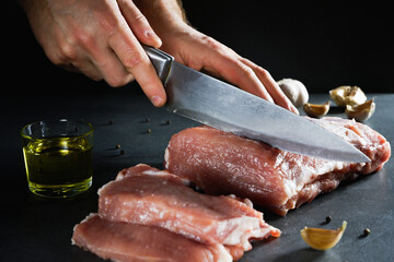 Raw meat. Juicy, appetizing chop with a piece and cut with spices and oil on a gray background.