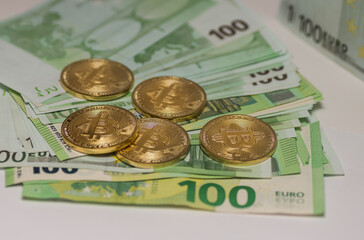 five golden bitcoins lying on many 100 euro bills