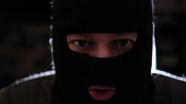 A man in a robber mask speaks and looks at the camera. Threats, blackmail concept.