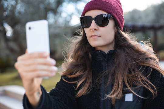 Woman Wearing Red Beanie And Sunglasses Taking A Selfie Outdoor