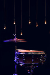 Fototapeta na wymiar Snare drum and hi-hat in the dark on a blurred background with lights.