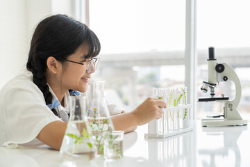 Happy Asian girl scientists learning and doing analysis for germs with glassware and microscope in the laboratory. Educational. Early development of children. Research and development concept