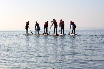People row on SUP at lake at calm winter day