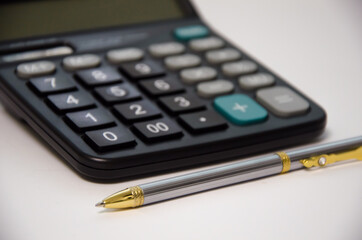 calculator and pen lie on a white background