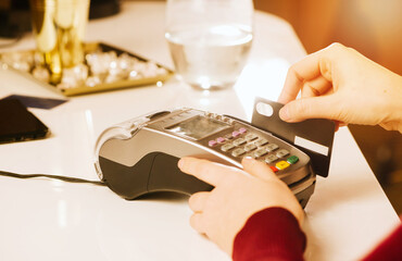 Client stand near the bar counter, terminal, credit card payment, close-up, view of the device, non-cash method of paying bills in the concept of commercial premises