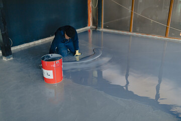 The worker applies gray epoxy resin to the new floor