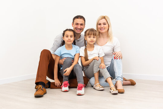 Happy family sitting on wooden floor. Father, mother and child having fun together. Moving house day, new home concept