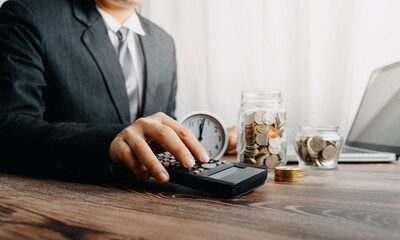 businesswoman holding coins putting in glass with using smartphone and calculator to calculate concept saving money for finance accounting