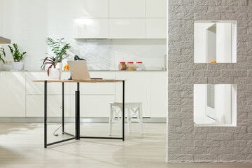 Working from home - a laptop and an organizer on a kitchen table with kitchen in the background.