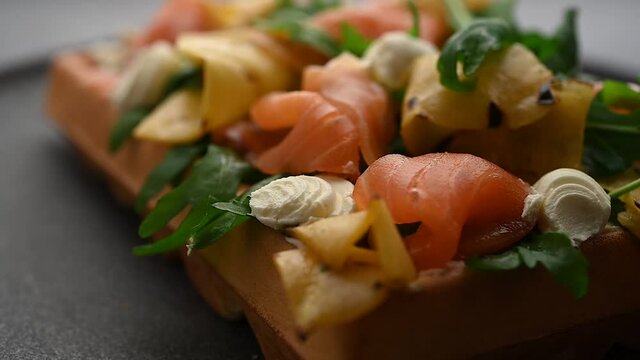 Delicious freshly baked waffle with smoked salmon slices on table.