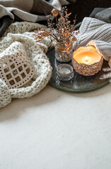 Fototapeta na wymiar Cozy home composition with a burning candle and knitted elements.