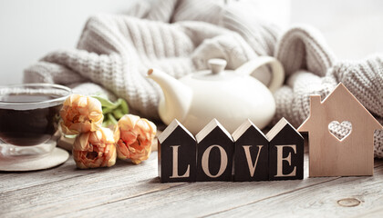 Fototapeta na wymiar A cozy composition for Valentine's Day with the decorative word love, a cup of tea and flowers.