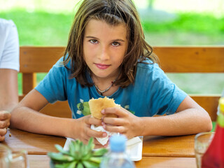 Fototapeta premium Child eating a hamburger with french fries