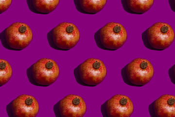 Seamless pattern with pomegranates on a purple background. Tropical abstract background. Pomegranate fruit with hard shadows