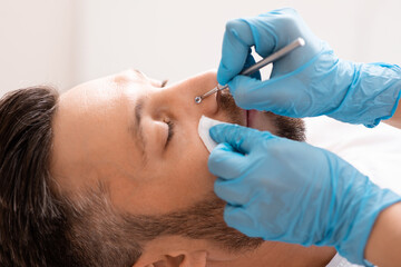 Middle-aged man having face cleansing treatment at beauty salon